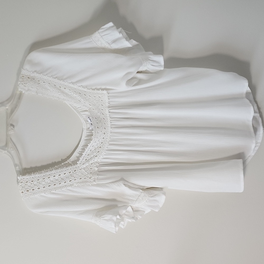 White flowy blouse with lace trimming.